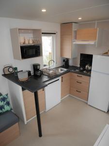 eine Küche mit schwarzer Arbeitsplatte und weißem Kühlschrank in der Unterkunft Blue Camargue - Le Grau du Roi in Le Grau-du-Roi