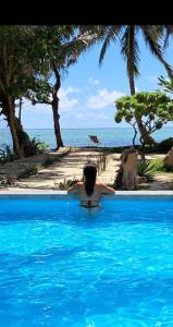 a person in a swimming pool looking at the ocean at Piscine rien que pour vous, propriété entière face au lagon, les pieds dans l 'eau, cuisine équipée & wifi Le Boraha Beach Lodge 90 m2 in Sainte Marie