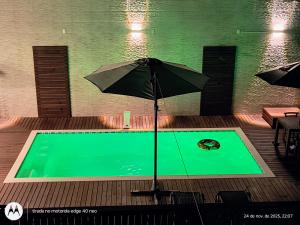 a pool with an umbrella in the middle of it at Acomodação Cambirela in Palhoça