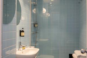 une salle de bain carrelée bleue avec un lavabo et une douche dans l'établissement Sixties Ramblas, à Barcelone 40 autres photos