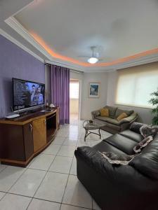 Una sala de estar con un sofá y un televisor de pantalla plana. en Apto a 80 metros do mar para 8 pessoas, en Itapema