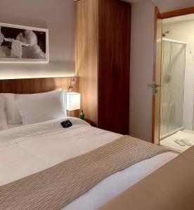 um quarto com uma cama grande e um chuveiro em Promenade Soho Campos dos Goytacazes em Campos dos Goytacazes