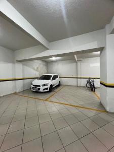 un garaje con un coche blanco aparcado en él en Apto a 80 metros do mar para 8 pessoas, en Itapema