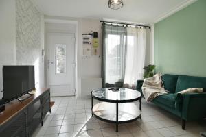 un soggiorno con divano verde e tavolo in vetro di Le Mont Servin - Entre Rennes et St-Malo a Lanhélin