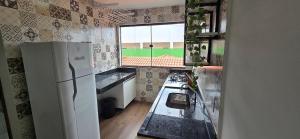 a kitchen with a refrigerator and a window at Apartamento Barra Vento 2 in Guriri