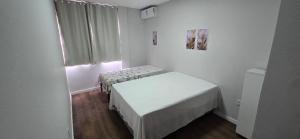 a small room with two beds and a window at Apartamento Barra Vento 2 in Guriri