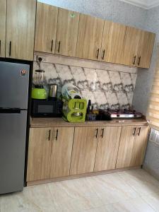 Una cocina con gabinetes de madera y un refrigerador negro. en ELLEX SLEEVES APARTMENTs, en Ibadán