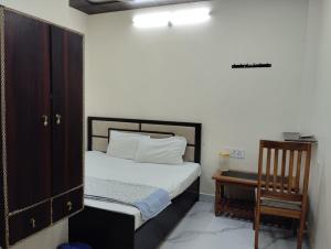 een slaapkamer met een bed en een houten kast en een stoel bij Maa tulsi guest house in Ayodhya