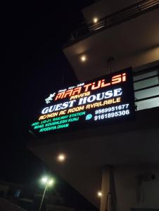 een bord aan de zijkant van een gebouw 's nachts bij Maa tulsi guest house in Ayodhya