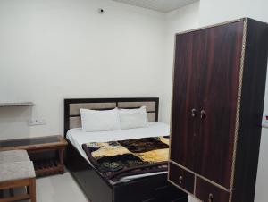 een kleine slaapkamer met een bed en een houten kast bij Maa tulsi guest house in Ayodhya