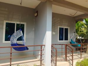 a porch with two blue swings on a house at Aasare Home Stay Gokarna in Kumta