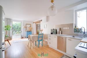 a kitchen with white cabinets and a table with chairs at Orves - Seine-Saint-Denis - CI - Elegance and comfort with garden for 2 people in Le Pré-Saint-Gervais