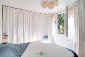 a white bedroom with a bed and a window at Orves - Seine-Saint-Denis - CI - Elegance and comfort with garden for 2 people in Le Pré-Saint-Gervais