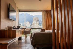 ein Hotelzimmer mit einem Bett und einem großen Fenster in der Unterkunft Hotel Estelar Parque de la 93 in Bogotá