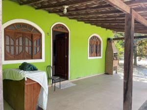 a green house with a table and a chair at Sitio do Piquira in São Francisco de Itabapoana