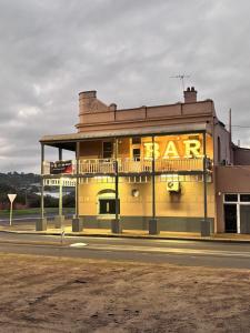 een geel gebouw met een bord waarop 'bar' staat bij The Club Hotel Collie in Collie
