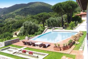 a swimming pool in a yard with chairs and a house at Residence La Chiusa di Rio, Rio nell'Elba in Rio nellʼElba