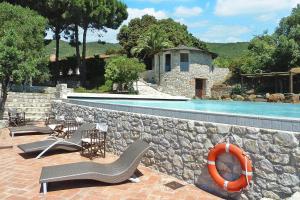 a stone wall with chairs and a swimming pool at Residence La Chiusa di Rio, Rio nell'Elba in Rio nellʼElba