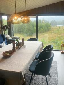 a dining room with a table and chairs and a large window at Renovated Cabin With Views In Trysil in Ljørdal +10 photos