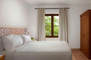 ein Schlafzimmer mit einem weißen Bett und einem Fenster in der Unterkunft Marriott’s Club Son Antem in Llucmajor + 52 Fotos