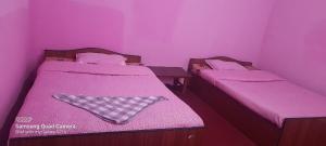 two beds in a room with pink walls at Saura Point Homestay in Nagarkot
