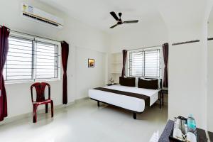 um quarto com uma cama, uma cadeira e janelas em Hotel O Elegant Residency Vandalur Zoo em Chennai