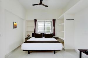 um quarto branco com uma cama e uma janela em Hotel O Elegant Residency Vandalur Zoo em Chennai