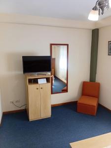 a room with a tv and a chair and a mirror at HOTEL CONTINENTAL COSQUIN in Cosquín