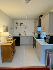 a large kitchen with white cabinets and a sink at Castle View Cottage at Snape Castle Mews in Bedale