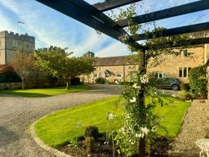 a garden in front of a brick building with white flowers at Castle View Cottage at Snape Castle Mews in Bedale