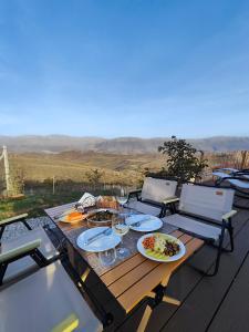 Sky Dome - Alushllari's Farm في بورغراديك: طاولة خشبية مع لوحات من الطعام وكؤوس النبيذ