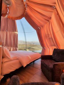 Sky Dome - Alushllari's Farm في بورغراديك: غرفة نوم بها خيمة برتقالية اللون تحتوي على سرير وأريكة +60 صورة