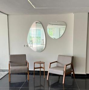 2 Stühle und ein Tisch in einem Zimmer mit 2 Spiegeln in der Unterkunft San Diego Suítes Manhuaçu in Manhuaçu