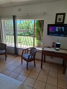 Casablanca Guesthouse في Carletonville: غرفة بسرير ومكتب وتلفزيون