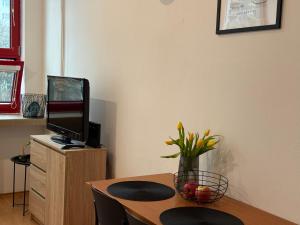 a room with a table with a television and a vase of flowers at Apartmán v centre Dubnice nad Váhom in Dubnica nad Váhom