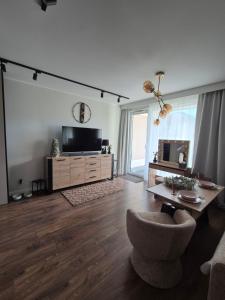 Una sala de estar con televisión y un sofá. en Apartament Leśny Zakątek, en Reda