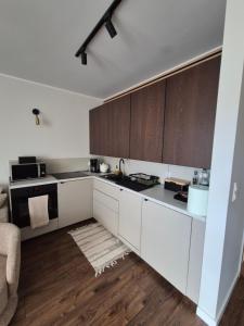 cocina con armarios blancos y suelo de madera en Apartament Leśny Zakątek, en Reda 3 fotos más