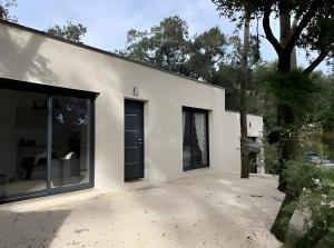 BuzignarguesにあるMaison Nichée Au Cœur Des Pinsの大きな窓と木のある白い建物