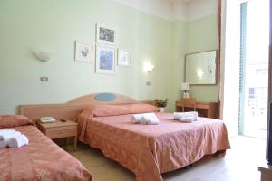 een slaapkamer met 2 bedden en roze lakens bij Hotel Massimo in Viareggio