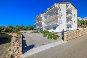 ein großes weißes Gebäude mit einer Steinmauer in der Unterkunft Apartments Sunshine D in Crikvenica