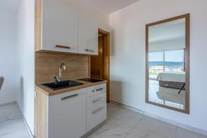 eine Küche mit weißen Schränken und einer Spüle und einem Fenster in der Unterkunft Apartments Sunshine D in Crikvenica + 98 Fotos