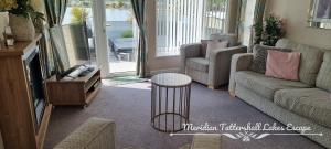 een woonkamer met een bank en een tafel bij Meridian Tattershall Lakes Escape - Lakeside lodge caravan with the fishing peg LUXURY HOT TUB in Tattershall