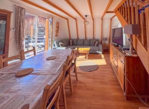 a living room with a long table and a television at Chalet Pointu in Isola 2000