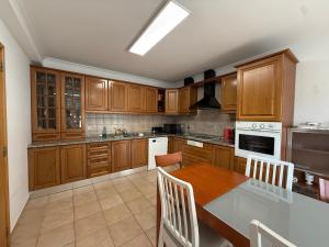 a kitchen with wooden cabinets and a table with chairs at Casa dos Cabecinhos in Oliveira do Hospital