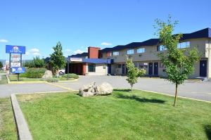 a building with rocks in the grass in front of a building at Canadas Best Value Inn Kelowna in Kelowna