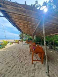 een houten bank onder een parasol op het strand bij Pantai Naama Bungalow 