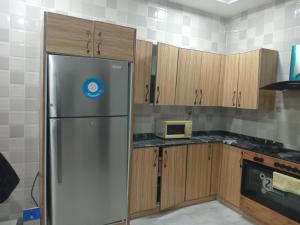 アブジャにあるMiriya Hotel and Apartmentsのキッチン(冷蔵庫、木製キャビネット付)