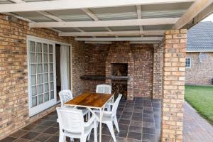patio con tavolo in legno e sedie bianche di Geluk Cottage a Somerset East