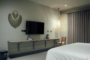 ein Schlafzimmer mit einem Bett und einem Schreibtisch mit einem Fernseher in der Unterkunft Greywood in Gili Trawangan