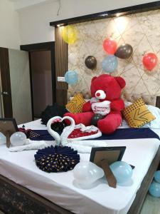 uma cama com um ursinho de pelúcia vermelho e balões em cima. em Hotel Sun em Bishnupur